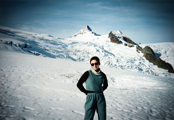 Author Paula Engborg standing against snow mountains with sunglasses