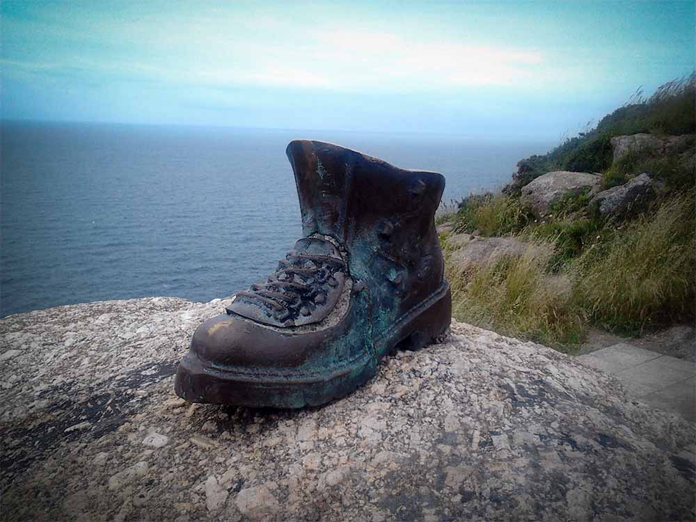 Shoe sculpture on a rock by the sea.