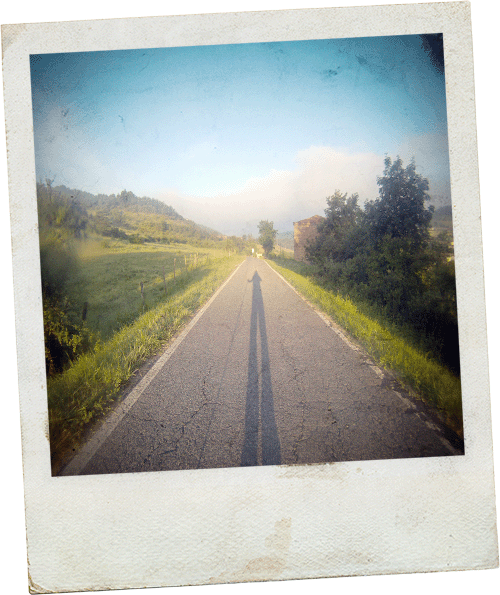 Polaroid image of a human shadow on a long road.